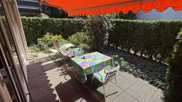 Gartensitzplatz mit Tisch, Liegestühlen und Sonnenstore