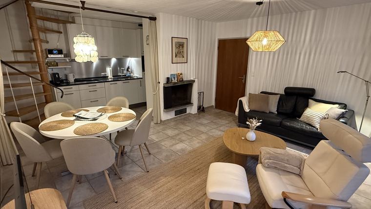 Wohn- und Essbereich mit Sofa, Cheminée, offener Küche und Wendeltreppe